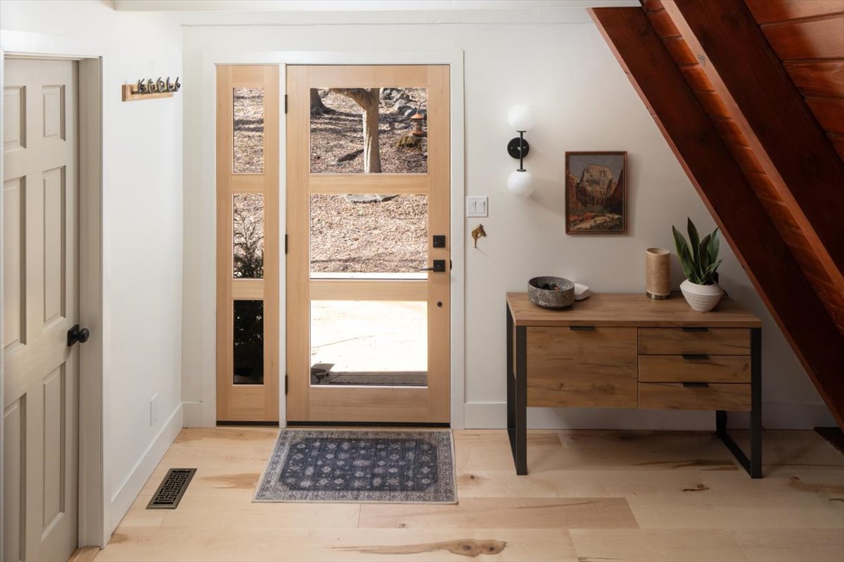 Entry area with window-paneled door, pale wood floor, dresser, and A-frame wall