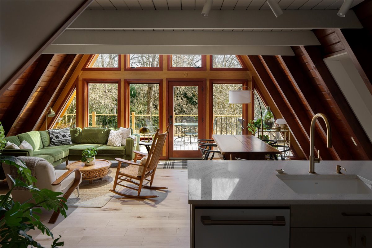 Open main floor with kitchen island, living area, tall windows, and A-frame ceiling