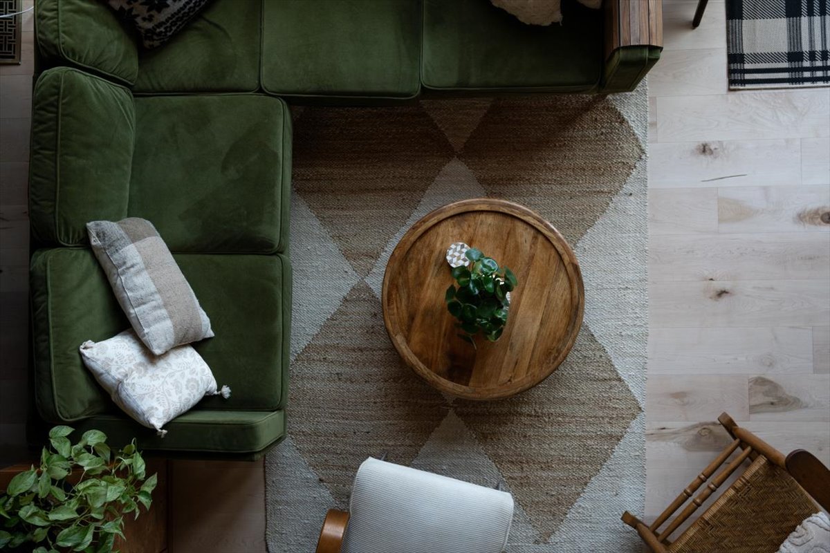 Overhead view of green sofa, lounge chair, round coffee table, and pale wood flooring