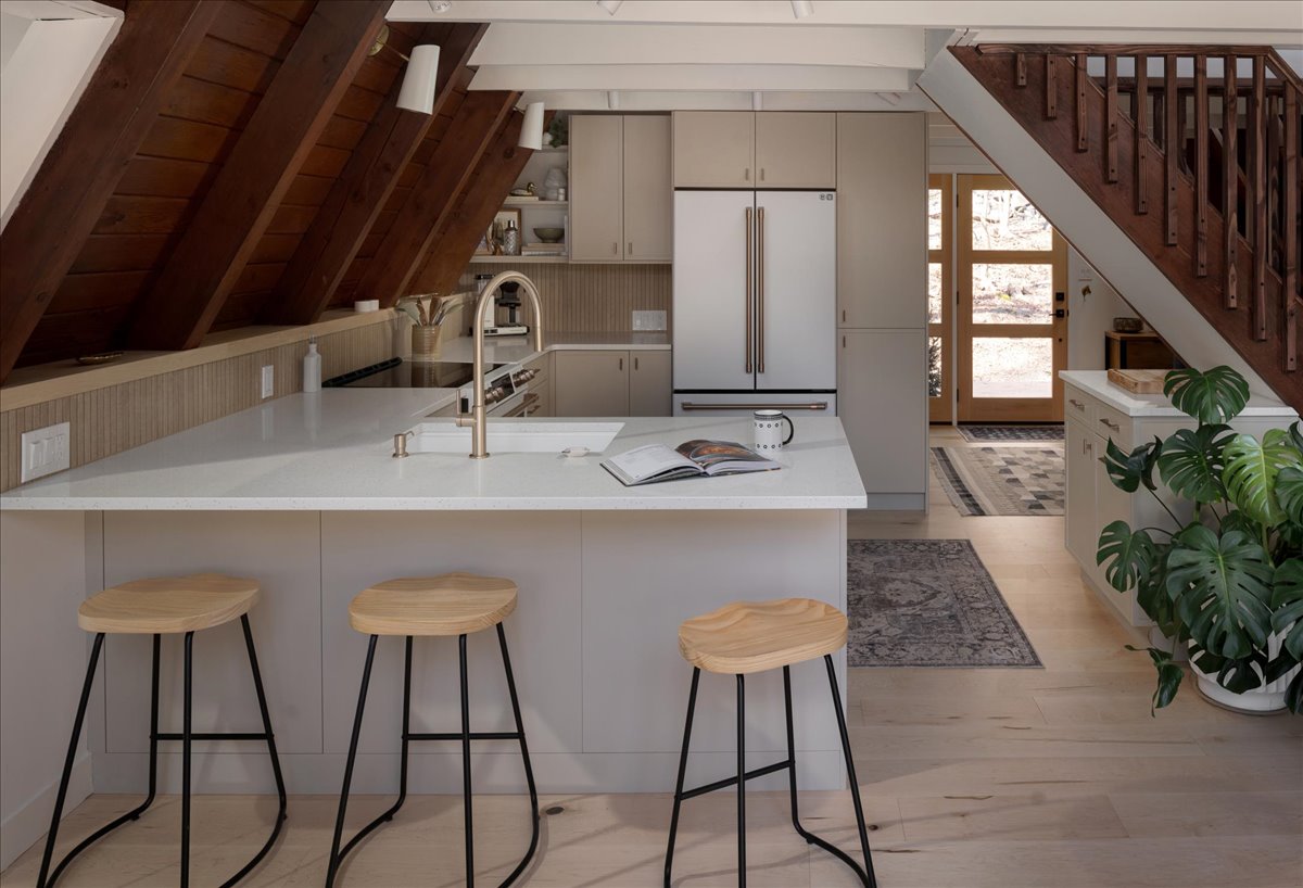 Kitchen island repositioned away from the angled A-frame wall with stools and white cabinetry