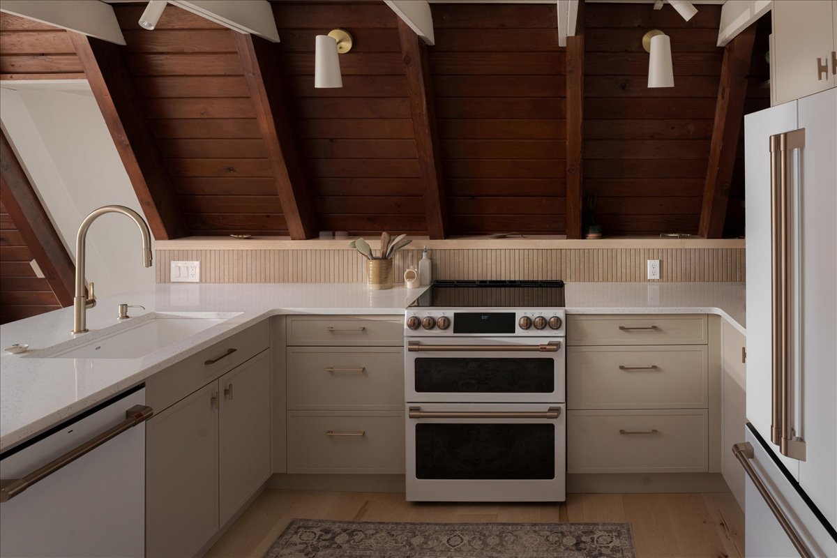 A-frame kitchen with updated range, cabinetry, tile backsplash, and work surfaces