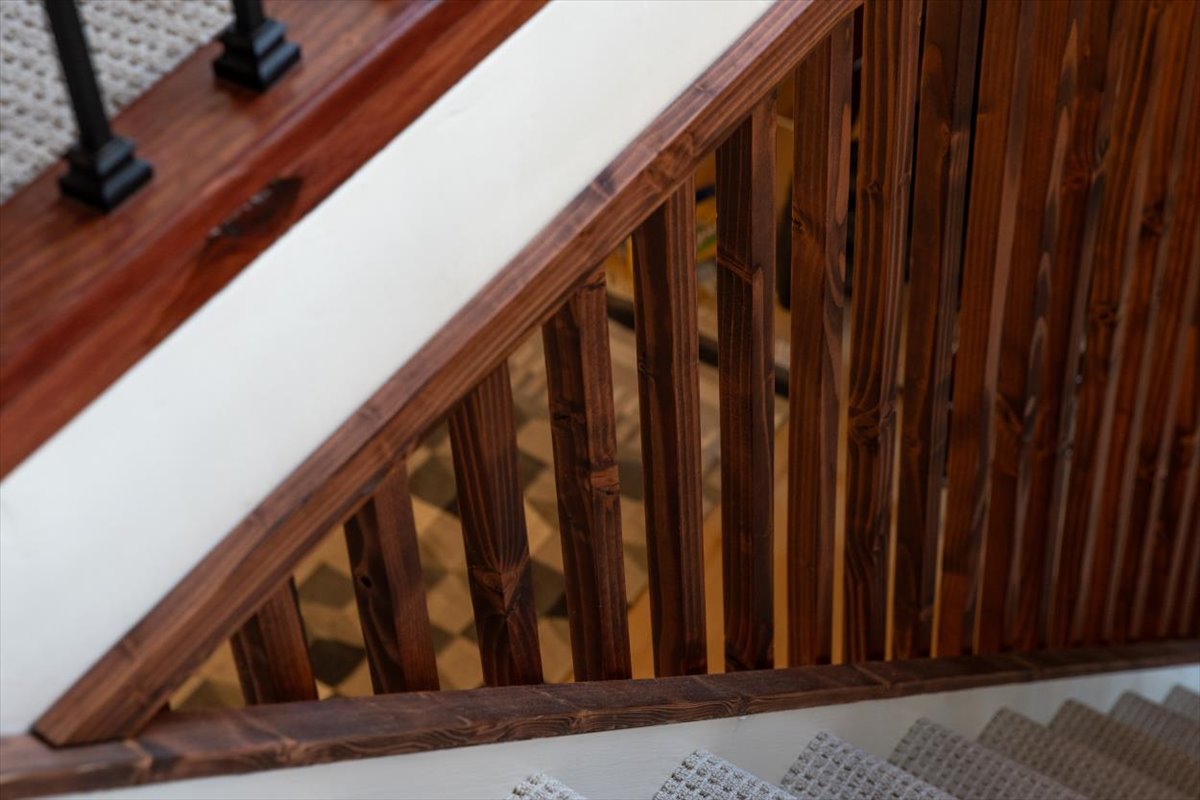 Stained wood railing and slat detail along the stair opening
