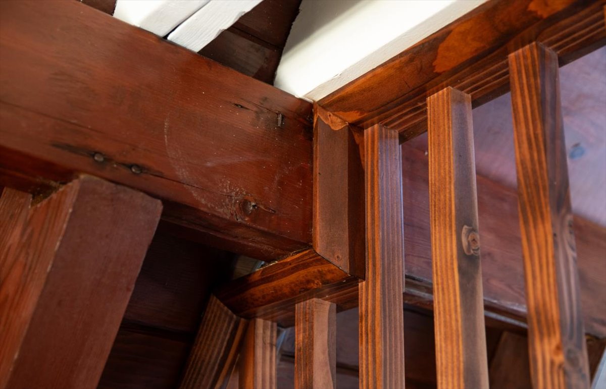Close detail of stained wood beams and new slat railing in the A-frame