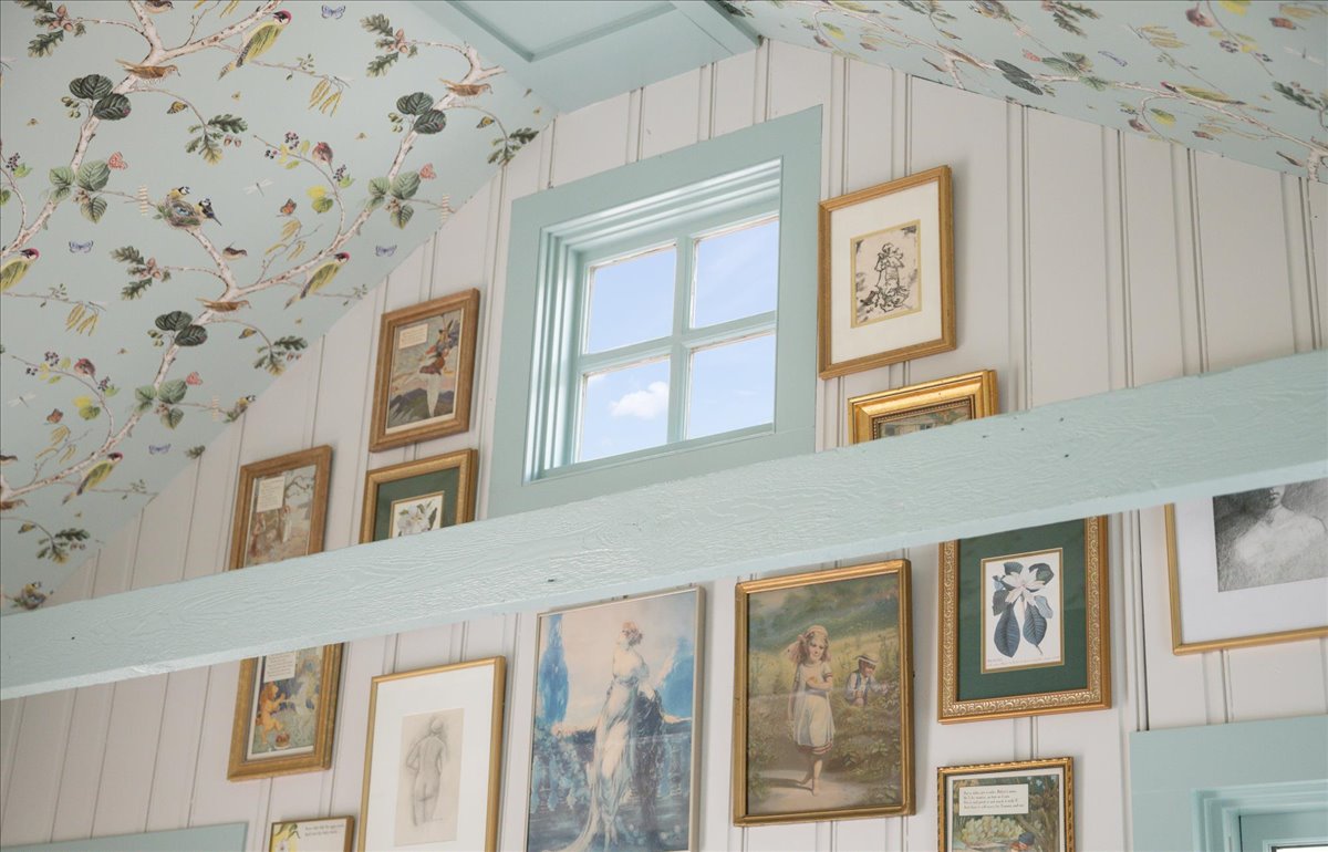 Patterned ceiling, blue-green trim, and collected framed art