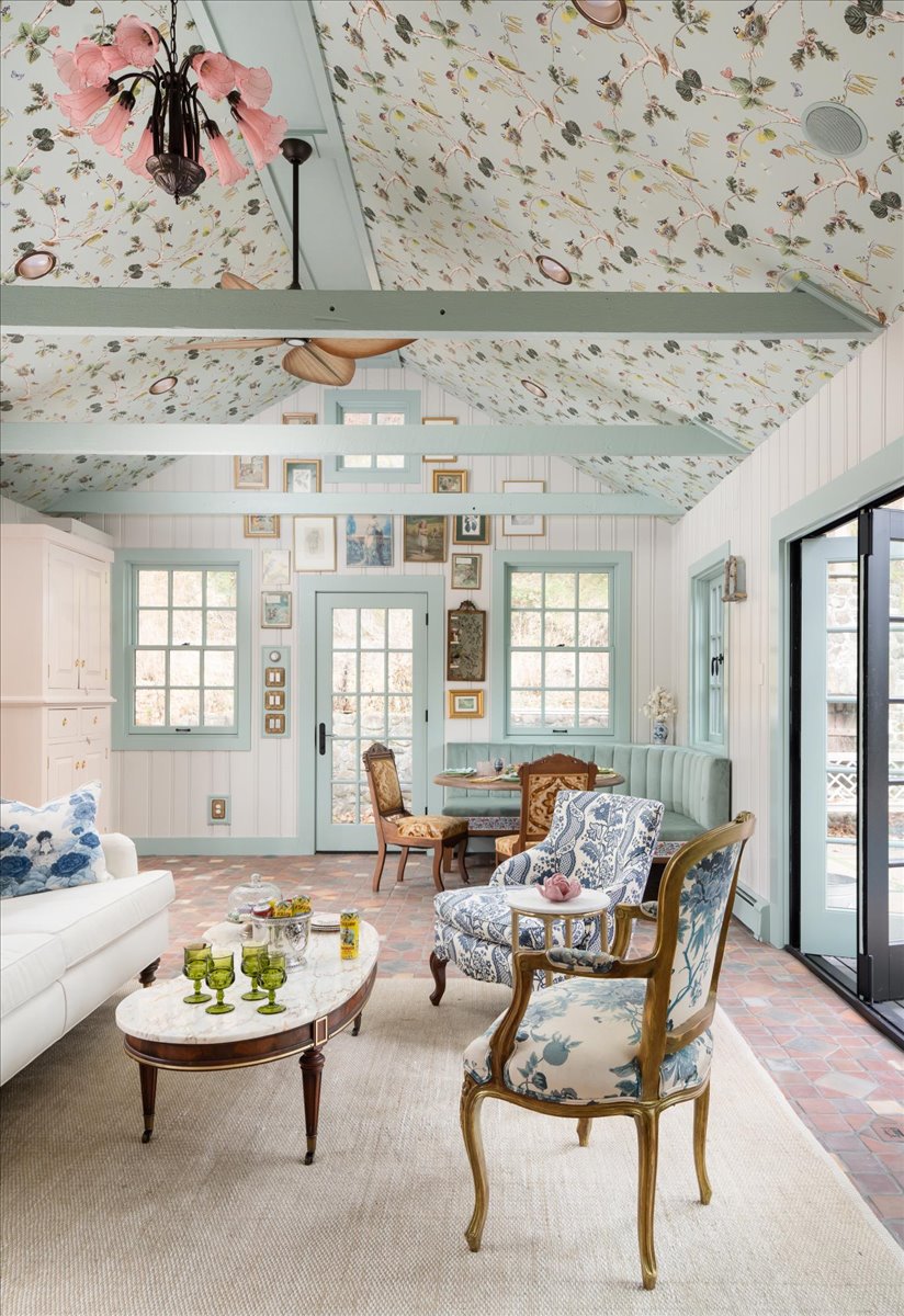 Pool house room with patterned walls, pale blue-green trim, seating, and kitchenette