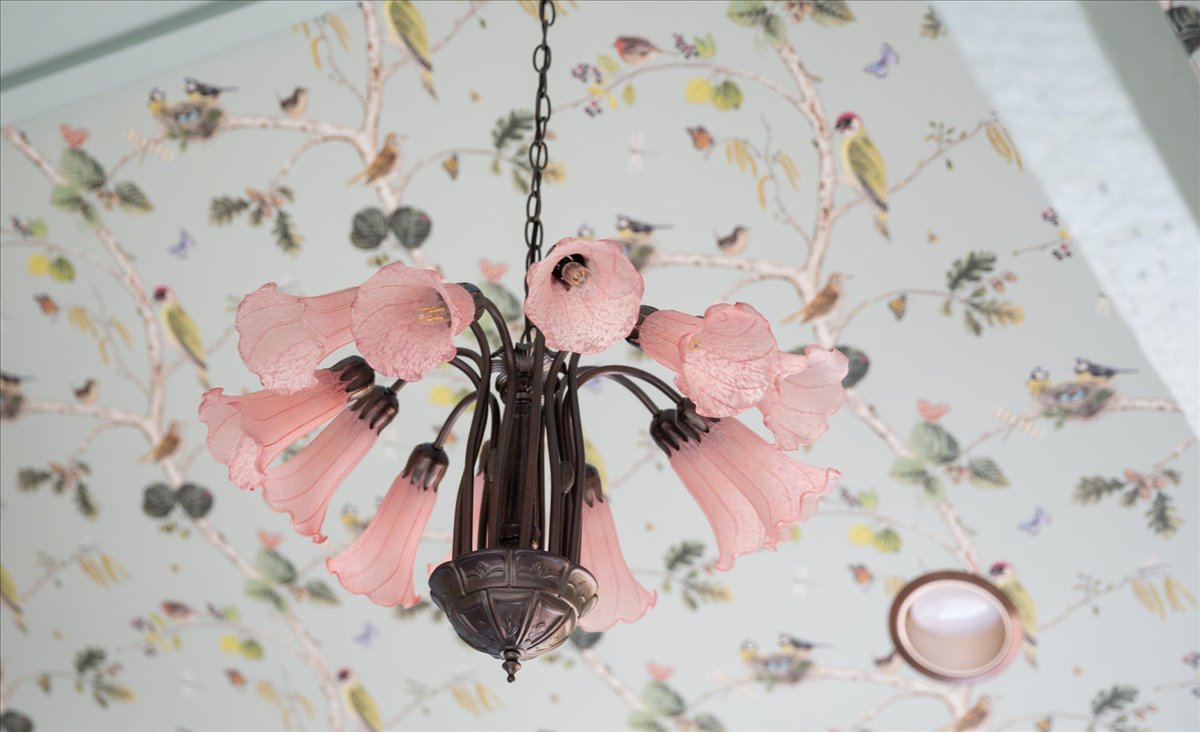 Flower-like ceiling light set against patterned wallpaper