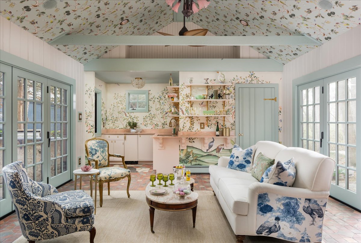 Crow's Perch pool house with patterned wallpaper, pale blue-green doors, white sofa, kitchenette, and layered seating
