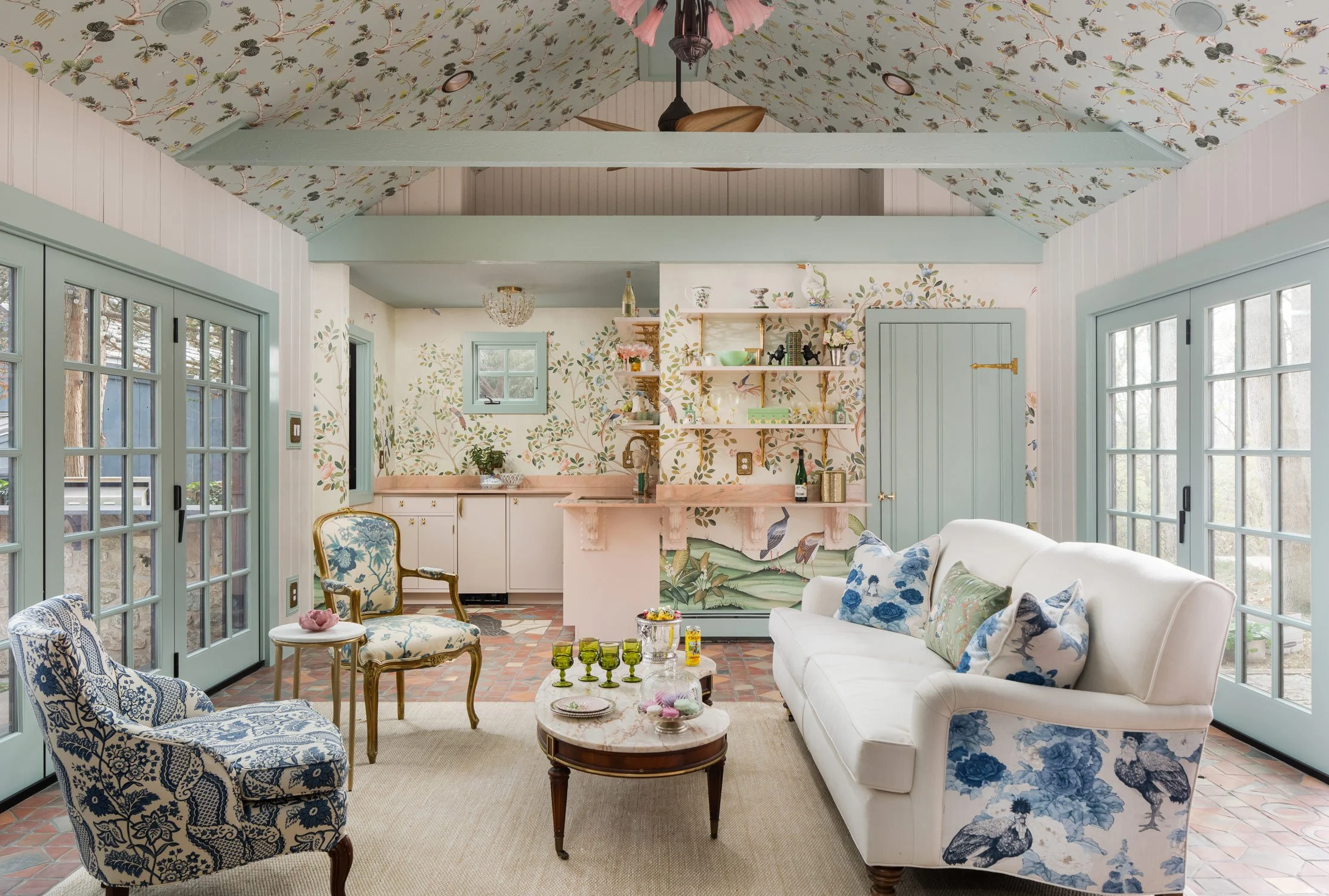 Crow's Perch pool house with pale blue-green doors, patterned upholstery, and a kitchenette
