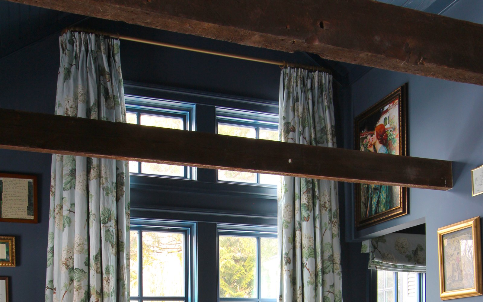 Vaulted ceiling with exposed wood beams, blue trim, and floral drapery